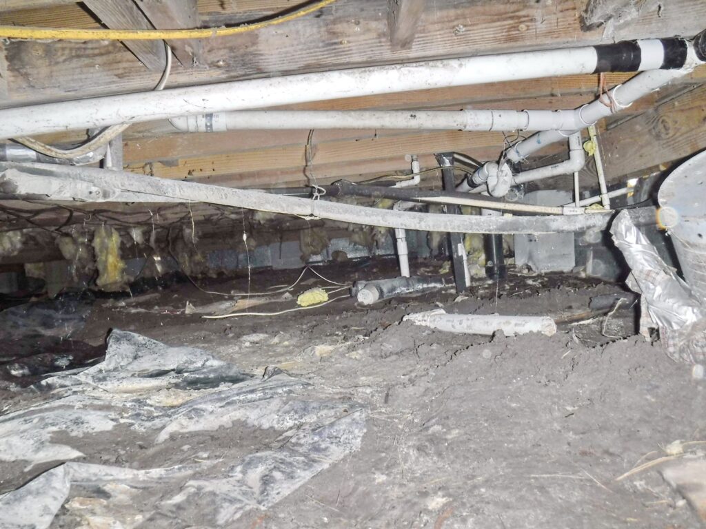 Picture of crawlspace showing multiple plumbing issues.